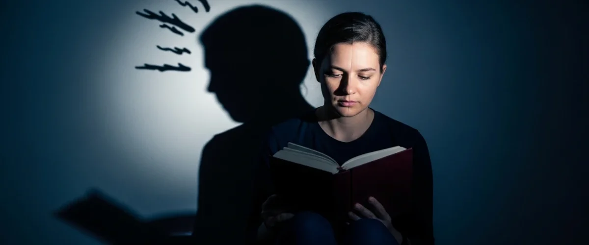 Pessoa lendo em ambiente escuro representando o arquétipo da sombra e o autoconhecimento