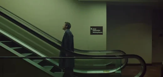 Frame do clipe “Aperture”, de Harry Styles: cantor em pé em uma escada rolante, em cenário urbano com luz fria e atmosfera cinematográfica.