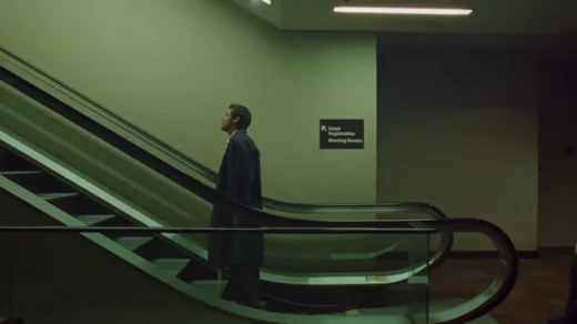 Frame do clipe “Aperture”, de Harry Styles: cantor em pé em uma escada rolante, em cenário urbano com luz fria e atmosfera cinematográfica.