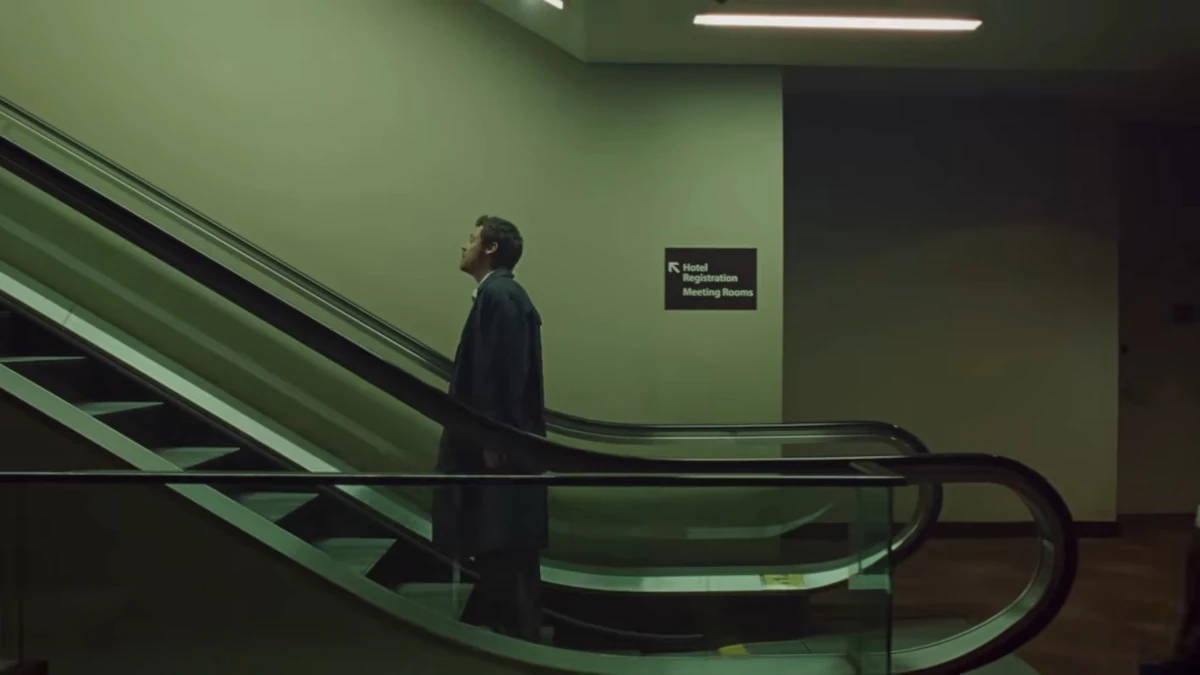 Frame do clipe “Aperture”, de Harry Styles: cantor em pé em uma escada rolante, em cenário urbano com luz fria e atmosfera cinematográfica.
