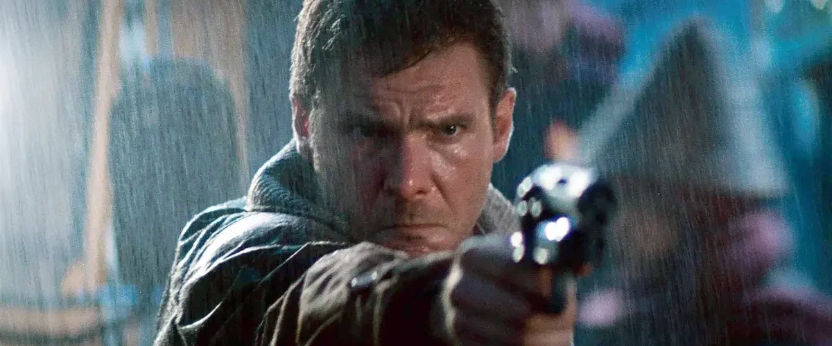 Rick Deckard aponta sua arma em cena de Blade Runner (1982), representando o conflito entre humanidade e replicantes