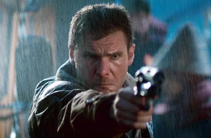 Rick Deckard aponta sua arma em cena de Blade Runner (1982), representando o conflito entre humanidade e replicantes