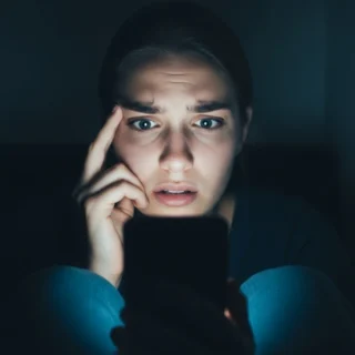 Mulher assustada olhando para o celular, representando a cultura do cancelamento e a autocensura nas redes sociais