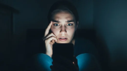 Mulher assustada olhando para o celular, representando a cultura do cancelamento e a autocensura nas redes sociais