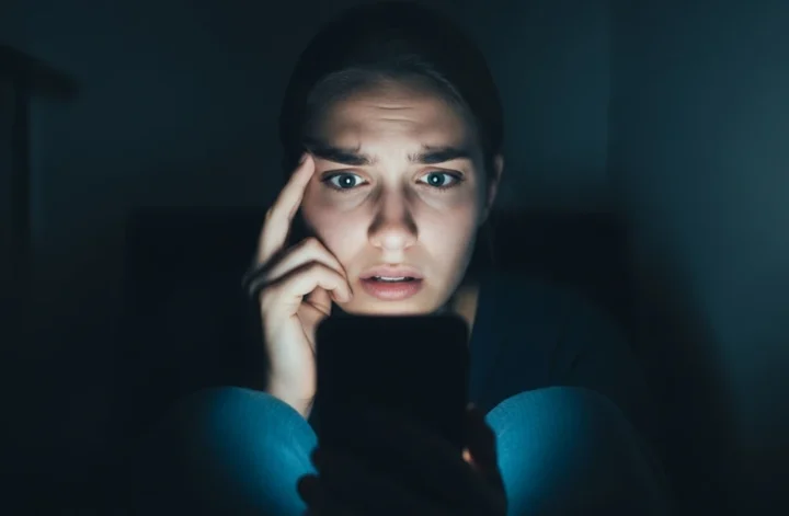 Mulher assustada olhando para o celular, representando a cultura do cancelamento e a autocensura nas redes sociais