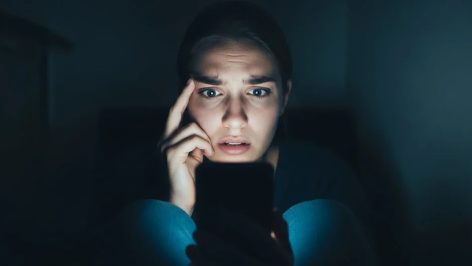 Mulher assustada olhando para o celular, representando a cultura do cancelamento e a autocensura nas redes sociais