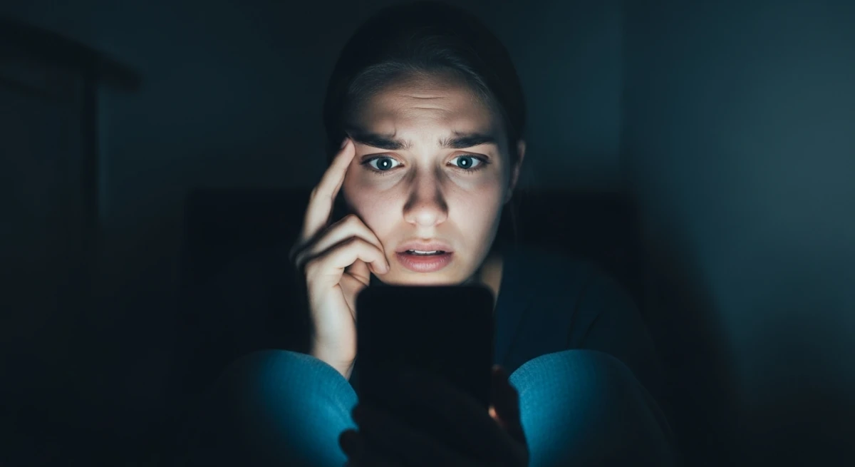 O Fim da Graça: cancelamento, culpa e a asfixia do humano na era digital 1 Mulher assustada olhando para o celular, representando a cultura do cancelamento e a autocensura nas redes sociais