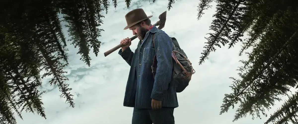 Joel Edgerton como Robert Griner com um machado na neve em cena do filme Sonhos de Trem (2024)