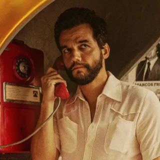 Wagner Moura em cena do filme O Agente Secreto usando um orelhão durante a ditadura militar no Brasil