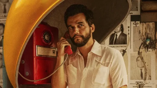 Wagner Moura em cena do filme O Agente Secreto usando um orelhão durante a ditadura militar no Brasil