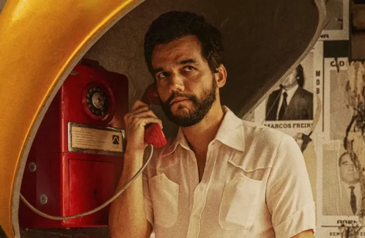 Wagner Moura em cena do filme O Agente Secreto usando um orelhão durante a ditadura militar no Brasil