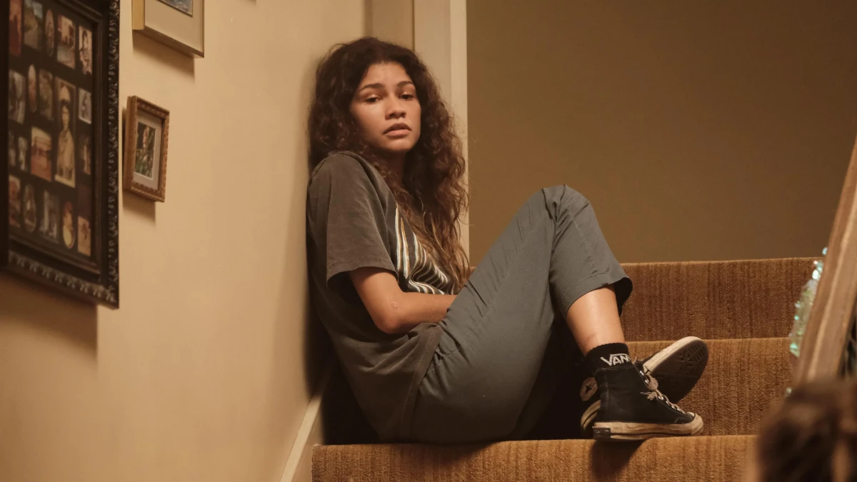 Rue Bennett sentada na escada em Euphoria, expressão introspectiva, estética dramática da série
