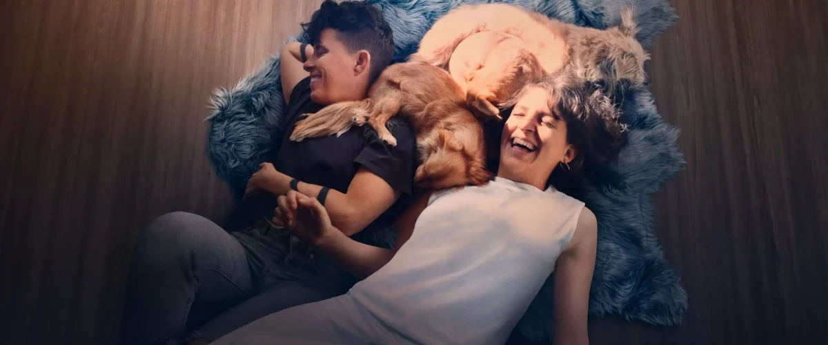 Casal de poetas deitado no chão com cães em cena do documentário Embaixo da Luz de Neon