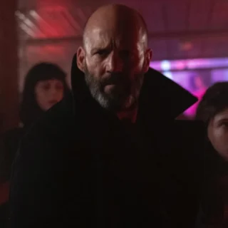 Jason Statham em cena do filme Missão Refúgio (2026) ao lado da jovem Jessie em ambiente iluminado por neon