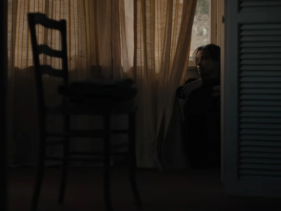 Cena do clipe de “Be With You” do Muse mostrando figura solitária em ambiente escuro com luz suave entrando pela janela