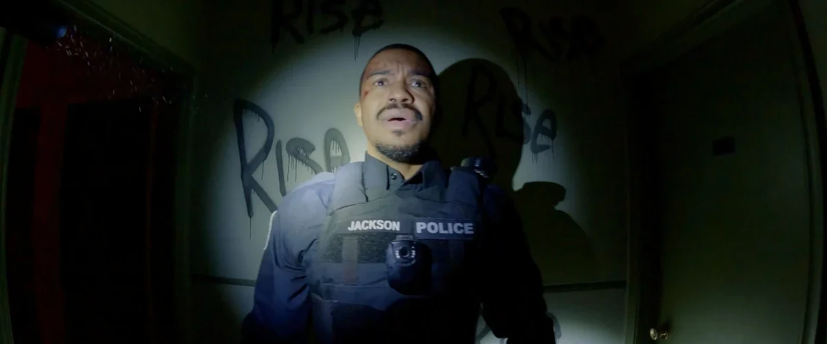 Policial com câmera corporal em cena do filme POV: Presença Oculta (Bodycam), terror found footage de Brandon Christensen.