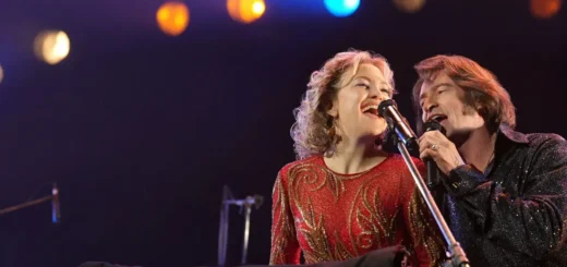 Hugh Jackman e Kate Hudson cantando no palco no filme Song Sung Blue Um Sonho a Dois