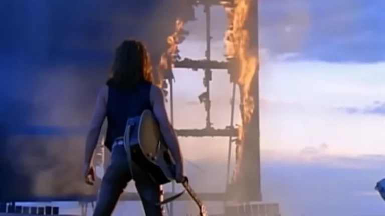 Jon Bon Jovi foi indicado ao Oscar — e isso revela mais sobre legitimidade cultural do que sobre música 1 Jon Bon Jovi com violão diante de uma estrutura em chamas no videoclipe Blaze of Glory, música indicada ao Oscar por Young Guns II.