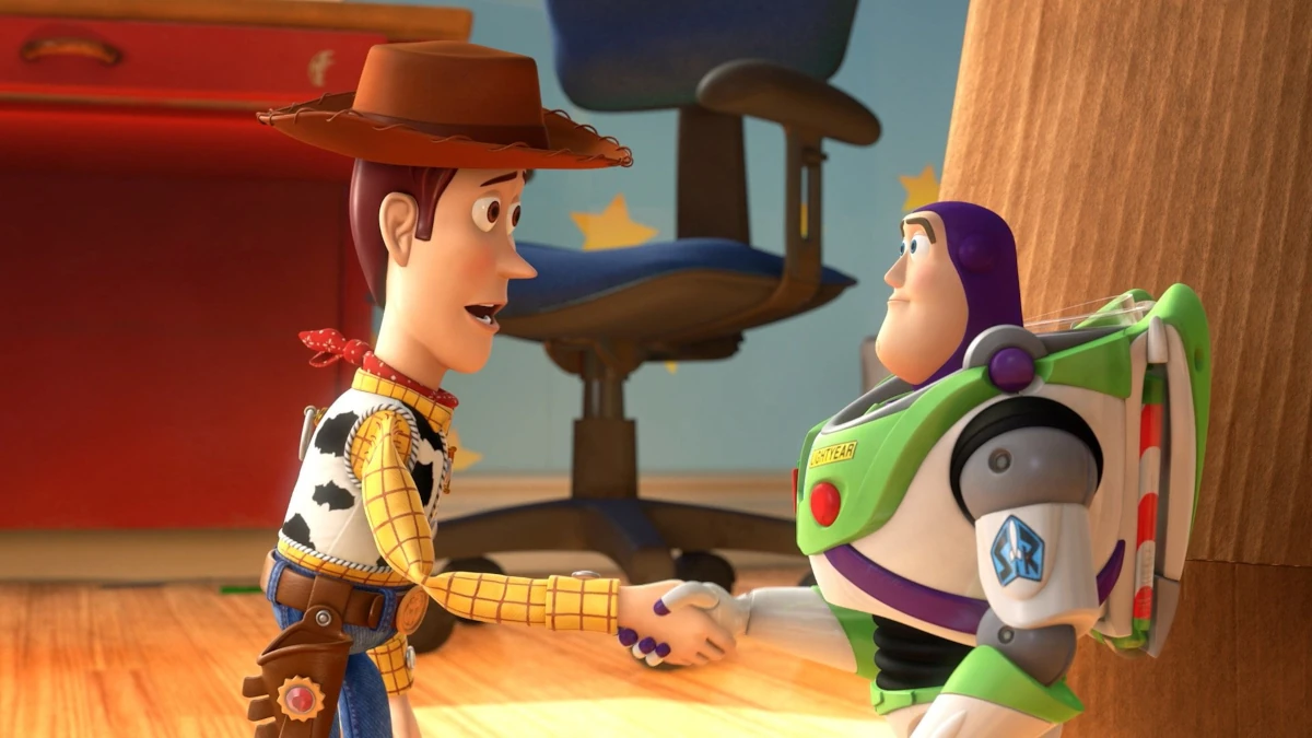 Woody e Buzz Lightyear apertam as mãos em uma cena de Toy Story 3, simbolizando amizade, despedida e amadurecimento.